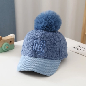 Detail of blue teddy velvet baby baseball cap with fur pompom and letter M embroidery