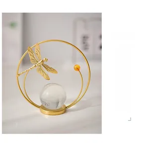 Detail of a gold iron dragonfly ring ornament with a clear crystal ball and amber bead