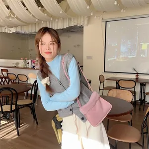 Sac bandoulière en peluche rose avec texture suédée porté avec une tenue décontractée