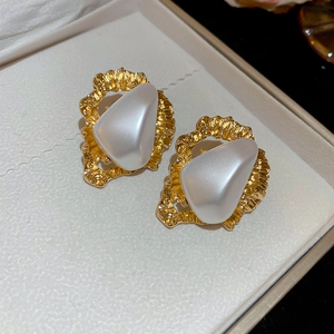 Détail des boucles d'oreilles dorées martelées avec grandes perles blanches