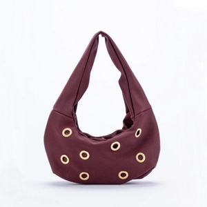 Burgundy faux suede crescent shoulder bag with golden metal grommet decorations