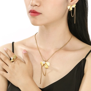 Elegant gold bow jewelry set with pearls featuring necklace earrings and ring on model