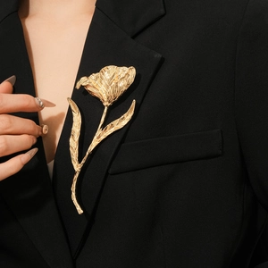 Close-up of golden tulip flower brooch on a black suit lapel with metal texture