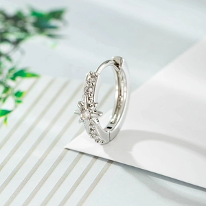 Micro shot of a silver hoop earring with micro-pasted zircons and a central hex star