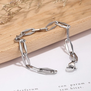 Macro detail of geometric interlocking stainless steel chain links on wooden tray