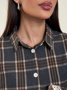 Close-up of classic dark plaid shirt fabric with white buttons and silver drop earrings