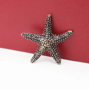 Vintage brass starfish figurine with detailed beaded texture on a red background