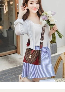 Brown checkered crossbody bag with red base and branded wide strap in a street style setting