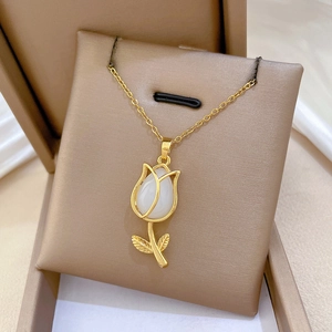 Detail of gold tulip necklace with white gemstone on a brown jewelry display cushion
