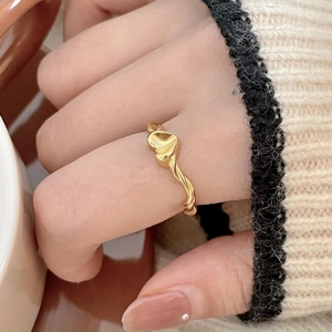 Close-up of golden heart-shaped ring with twisted band texture on finger