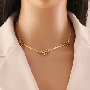 Detailed view of golden snake chain necklace with three elegant bow pendants on a model