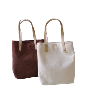Brown and cream corduroy tote bags with leather straps on a clean white background