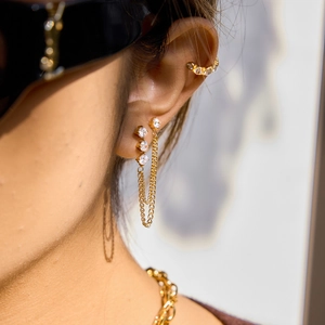 Detailed close-up of 18K gold-plated chain earrings with white zircon accents on ear