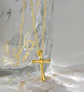 Close-up of golden S925 sterling silver cross pendant with lava texture on stone base