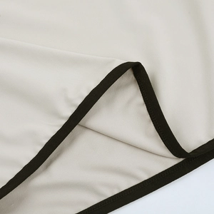 Detailaufnahme des beigen Strickkleides mit schwarzen Paspeln und hochwertiger Nahtführung