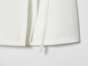 Detail of white dress fabric showing fine stitching and adjustable waist tie design