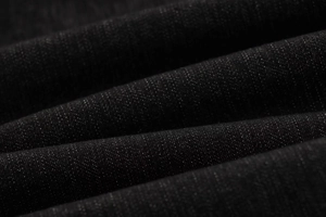 Dettaglio del tessuto denim nero premium con trama a saia e pieghe morbide naturali
