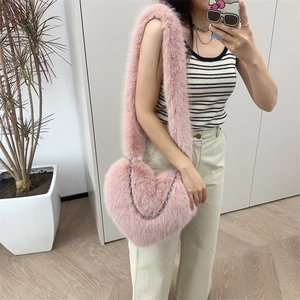 Close-up of pink plush heart-shaped bag with a fluffy strap and silver metal chain