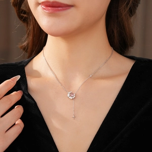 Détail du collier pendentif fleur rose et croix sur le décolleté d'un mannequin