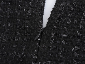 Makro-Detail des schwarzen Tweed-Stoffs mit Metallic-Garn und verdecktem Reißverschluss