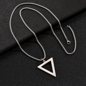 Detailed close-up of a silver triangle pendant on a box chain over a dark textured surface