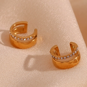 Détail macro du cuff d'oreille double doré avec zircons micro-sertis sur tissu satiné