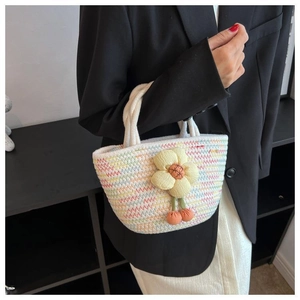 Detail of colorful woven handbag featuring a 3D yellow fabric flower and cherry charm
