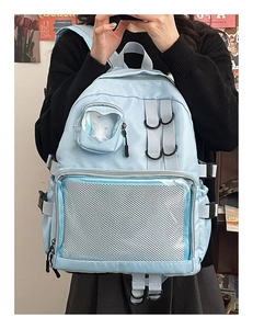 Detail of light blue nylon backpack featuring multi-pocket design and clear window