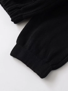 Makroaufnahme der gerippten Bündchen einer schwarzen Strickjacke mit Textur-Detail