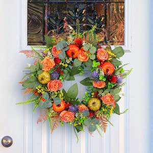 Autumn wreath with orange roses and pumpkins on a white wooden door for home decor