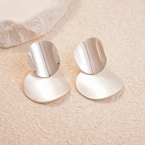 Close-up of geometric silver earrings with matte brushed and polished metal finishes