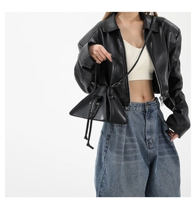 Detail view of a black triangle leather handbag styled with a trendy punk outfit