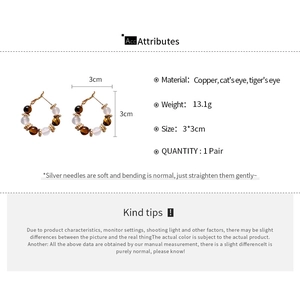 Detail view of gold-plated hoop earrings with cat eye beads and tiger eye stones