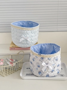 Detail of blue lace storage baskets with quilted patterns and soft ribbon bows