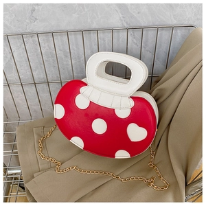 Detail of red polka dot heart handbag with gold chain strap and ruffled handle