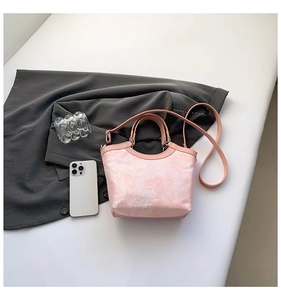 Close-up of pink bucket bag with embossed floral texture and silver hardware details