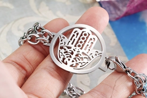 Macro shot of silver Hamsa Hand hollowed-out charm on double layer chain bracelet