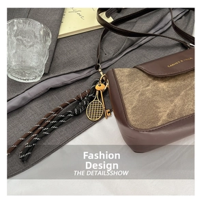 Detail of vintage crossbody bag with brown leather, canvas panels and golden charms