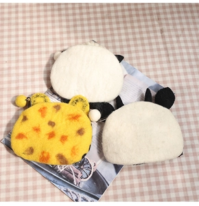 Macro detail of three handmade wool felt animal coin purses on a plaid background