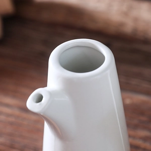 Botella de aceite de cerámica blanca minimalista con boquilla sobre fondo de madera