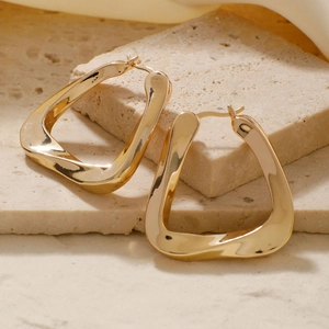 Detail view of gold U-shaped geometric earrings on a textured stone display