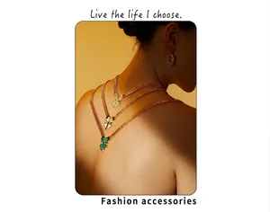 Stack of gold clover necklaces with green malachite and diamond detail on Cuban chain