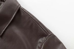 Close-up of the precise stitching and dark brown leather texture on bomber jacket shoulder