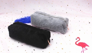 Detail of plush pencil cases in black and gray with rose gold zippers on pink mesh