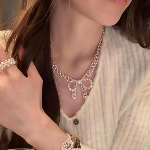 Elegant French style pearl necklace with bow pendant set worn by model in soft light