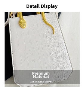Detail shot of white croc-embossed handbag with luxury gold snake-shaped handle