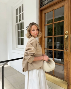 Detail of a chic beige stand collar flight jacket paired with a white long skirt and handbag