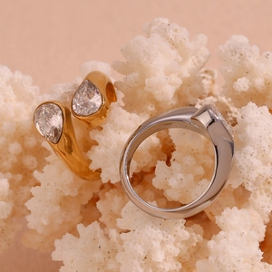 Macro shot of 18K gold and silver pear-shaped zircon rings on white coral background