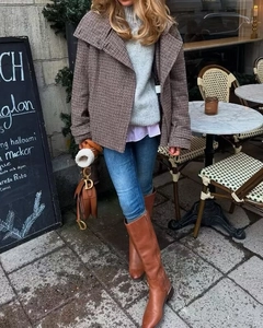 Outdoor street style view of a cropped plaid wool jacket with blue jeans and leather boots