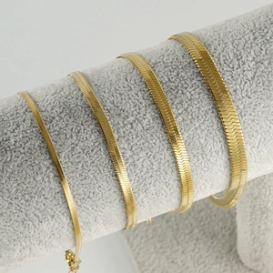 Flat herringbone blade chain bracelets in four different widths on a jewelry display stand